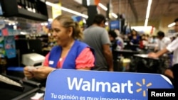FILE - A cashier smiles beyond a Walmart logo during the kick-off of the 'El Buen Fin' (The Good Weekend) holiday shopping season, at a Walmart store in Monterrey, Mexico, November 17, 2017.