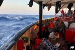 Seorang migran membaca ayat-ayat Alquran di atas kapal kemanusiaan Spanyol Open Arms saat tiba di dekat pantai Lampedusa di Laut Mediterania, Kamis, 15 Agustus 2019. (Foto: AP)