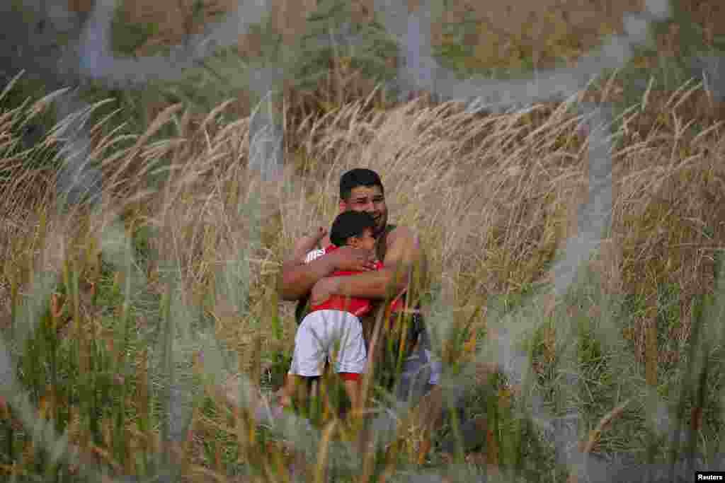 A migrant holds his child on the Serbian side of the fence in Asotthalom, Hungary. Hundreds of migrants spent the night in the open on Serbia&#39;s northern border with Hungary, their passage to western Europe stalled by a Hungarian crackdown to confront the continent&#39;s worst refugee crisis in two decades.