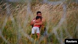 A migrant holds his child on the Serbian side of the fence in Asotthalom, Hungary, Sept. 15, 2015. 