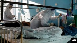 Medics wearing special suits to protect against coronavirus treat COVID-19 patients in an intensive care unit of a hospital in Volgograd, Russia, Nov. 21, 2021.