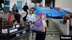 A family leaves a United Nations-run school sheltering displaced Palestinians, before making their way home after a ceasefire was declared, in the southern Gaza Strip, Aug. 27, 2014.