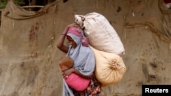 FILE - A displaced Somali woman carries a child and her belongings as she arrives at a temporary dwelling after fleeing famine in the Marka Lower Shebbele regions to the capital Mogadishu, Sept. 20, 2014. More recent shortages are linked to the El Nino weather phenomenon, which has proven to be one of the worst on record.