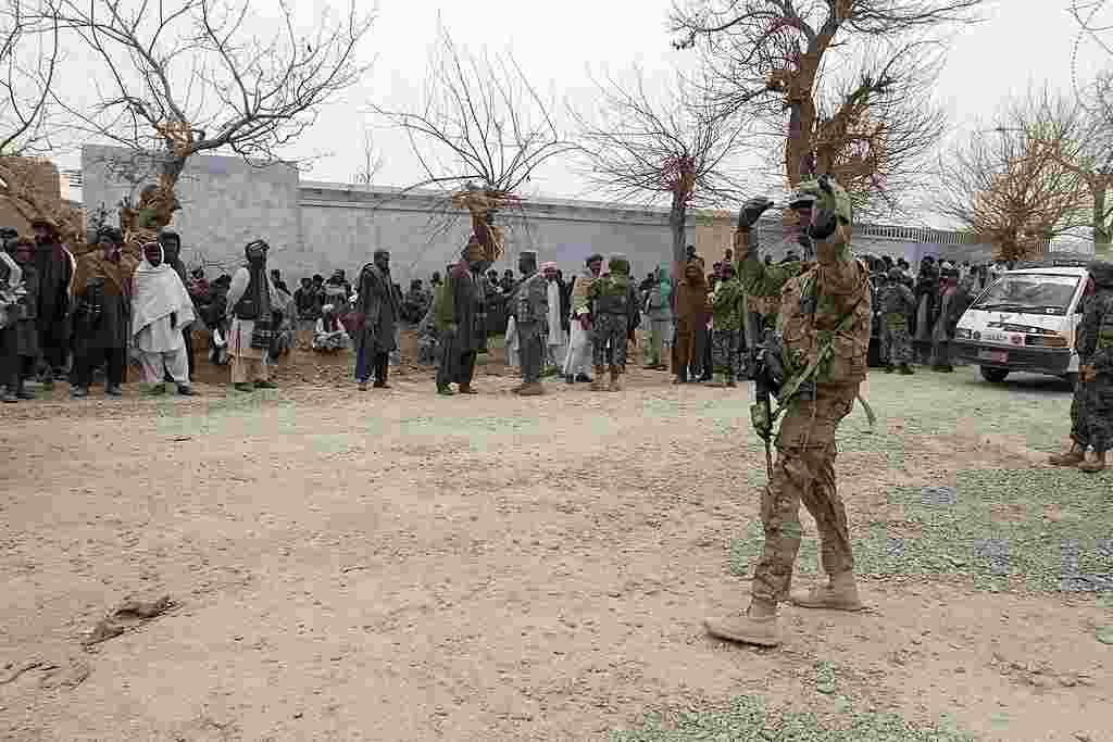 Seorang tentara AS mengarahkan lalu-lintas sementara warga lokal berkumpul di jalan di Panjwai (AP).