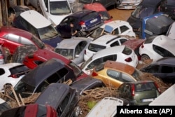 Residents look at cars piled up after being swept away by floods in Valencia, Spain, Oct. 30, 2024.