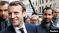 FILE - Emmanuel Macron, left, campaigns for the 2017 presidential election, flanked by Alexandre Benalla, right, head of security, in Rodez, France, May 5, 2017.