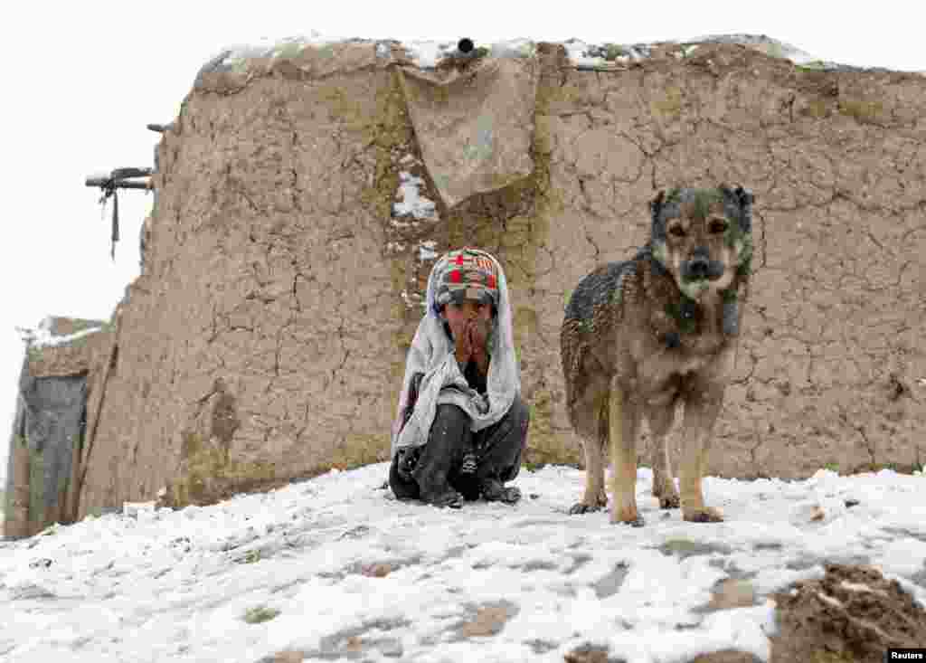 An internally displaced boy sits outside his shelter during snowfall in Kabul, Afghanistan.