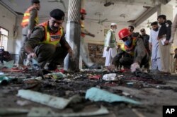 Pakistani rescue workers and police officers examine the site of a bomb explosion in an Islamic seminary, in Peshawar, Pakistan, Oct. 27, 2020.