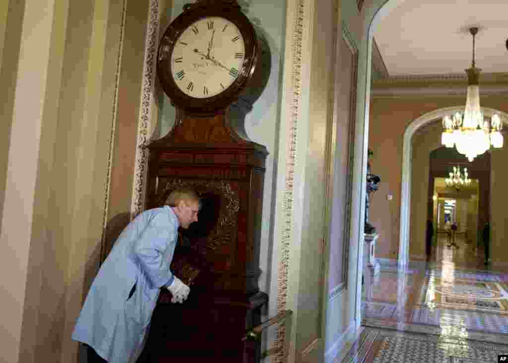 Richard Doerner, Museum Specialist for the U.S. Senate Commission on Art, listens to the Ohio Clock as he restarts it outside the Senate chamber on Capitol Hill, Oct. 17, 2013 in Washington. The clock stopped during the 16-day government shutdown because the workers that care for the clock were furloughed.