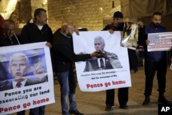 Palestinians hold posters of U.S. President Mike Pence as they protest his visit to Israel in Bethlehem, West Bank, Sunday, Jan. 21, 2018.