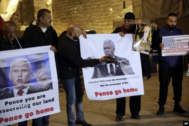 Palestinians hold posters of U.S. President Mike Pence as they protest his visit to Israel in Bethlehem, West Bank, Sunday, Jan. 21, 2018.