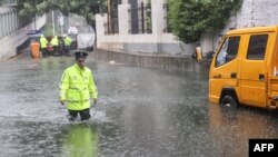 ตำรวจเดินฝ่าน้ำท่วมบนท้องถนนที่เป็นผลพวงจากไต้ฝุ่นทกซูรี ในเซียเหมิน มณฑลฝูเจี้ยนของจีน เมื่อ 28 กรกฎาคม