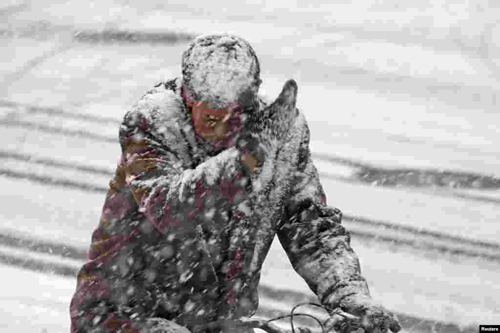 A man rides a bicycle along a street during a snowfall in Yantai, Shandong province, China.