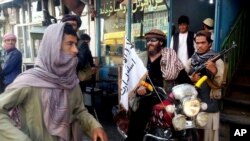 Seorang tentara Taliban duduk duduk di sepeda motornya yang dihiasi bendera Taliban di sebuah jalan di Kunduz, Afghanistan, 29 September 2015.