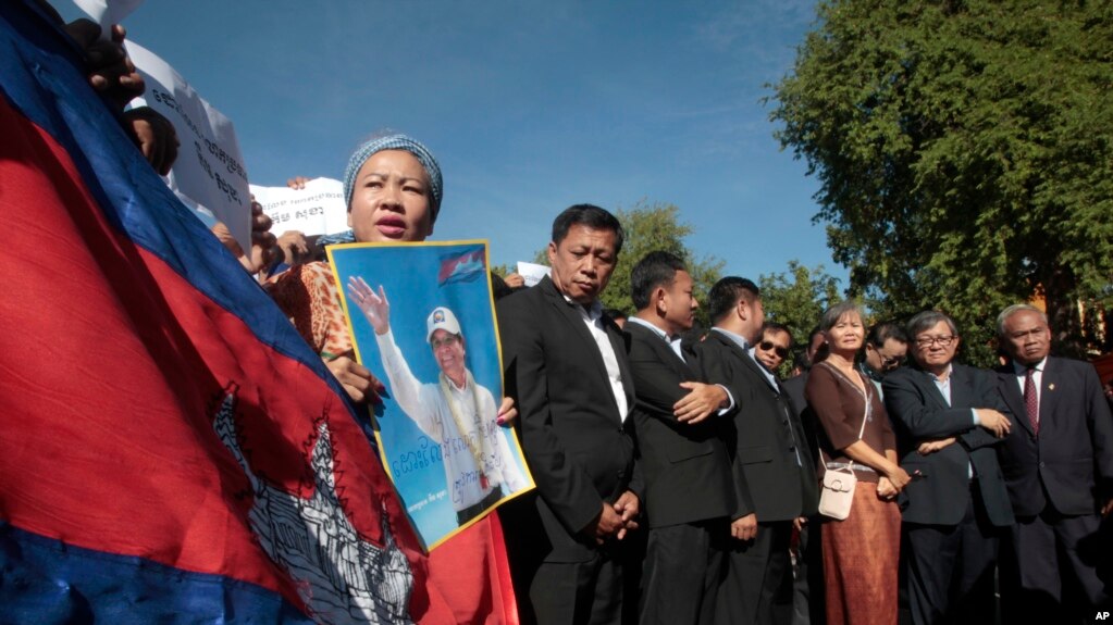 A supporter of the opposition Cambodia National Rescue Party holds a poster of the party leader Kem Sokha during a rally joined by lawmakers near an appeals court in Phnom Penh, Cambodia, Sept. 26, 2017. 
