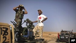 A former rebel fighter looks through binoculars as he stands in a convoy of revolutionary forces, moments before heading to the frontline in Bani Walid, at a checkpoint in Wadi Dinar, Libya, September 16, 2011.