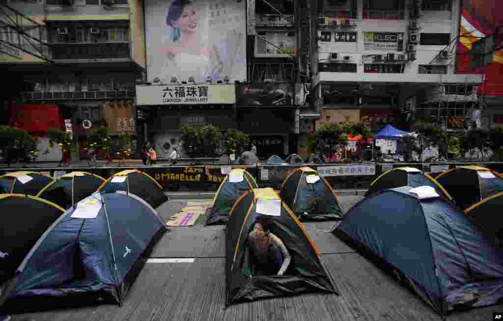 A pro-democracy demonstrator wakes from her tent in an occupied area of the Mong Kok district, Hong Kong, Oct. 16, 2014. 