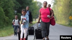 FILE - Members of a Haitian family walk toward the U.S.-Canada border from Champlain, N.Y., Aug. 11, 2017. Haiti has asked the U.S. government to extend TPS status for its nationals. 