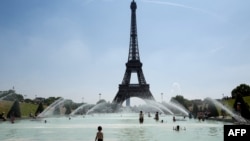 Warga dan turis mendinginkan diri di air mancur Trocadero di depan Menara Eiffel di Paris.