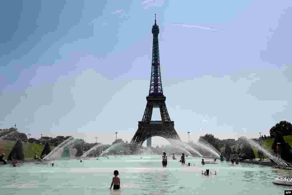 People cool themselves at the Trocadero Fountain in front of The Eiffel Tower in Paris on July 27, 2018, as a heatwave continues across northern Europe.