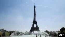 People cool themselves at the Trocadero Fountain in front of The Eiffel Tower in Paris on July 27, 2018, as a heat wave continues across northern Europe.