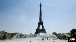 FILE - People cool themselves at the Trocadero Fountain in front of The Eiffel Tower in Paris on July 27, 2018, as a heatwave continues across northern Europe.