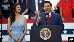 Florida Republican gubernatorial candidate Ron DeSantis, right, gestures as he stands with his wife, Casey, during a rally with President Donald Trump, Oct. 31, 2018, in Estero, Fla.