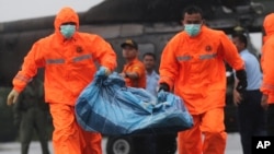 National Search and Rescue Agency personnel carry a bag containing parts of AirAsia Flight 8501 after being airlifted by a Singapore Navy Super Puma helicopter at the airport in Pangkalan Bun, Indonesia, Jan. 4, 2015. 