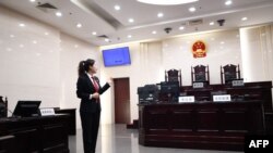 一名中国人民最高法院的工作人员站在法庭内向参观者做介绍。（2018年12月20日）