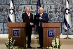 FILE - Israeli President Reuven Rivlin gives Israeli Prime Minister Benjamin Netanyahu a file during a nomination ceremony at the President's residence in Jerusalem, Sept. 25, 2019.