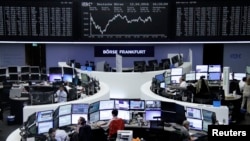 Traders work at their desks in front of the German share price index, DAX board, at the stock exchange in Frankfurt, Germany, April 12, 2016. 