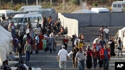 Newly arrived Syrian refugees walk to their tents in the Turkish border town of Reyhanli in Hatay province June 23, 2011, as others who are already placed rest in front of their tents.