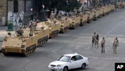 FILE - Egyptian army soldiers take their positions on top and next to their armored vehicles to guard an entrance of Tahrir Square, in Cairo. Obama administration is poised to slash hundreds of millions of dollars in military and economic assistance to Eg