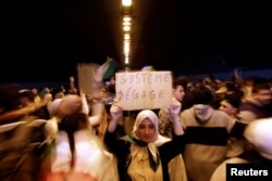 A woman takes part in a protest demanding immediate political change, in Algiers, Algeria March 12, 2019. Her sign reads: "System, go away."