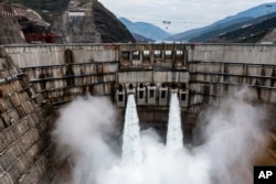 FILE - In this photo released by Xinhua News Agency, water is released from the dam of Baihetan hydropower station in Ningnan county, in southwestern China's Sichuan province on June 27, 2021.