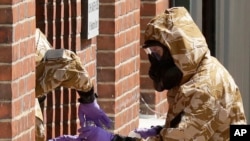 FILE - Specialist team members wear military protective suits during Novichok nerve agent cleanup operations in Salisbury, England, July 6, 2018.