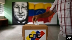 ARCHIVO - Un hombre deposita su voto frente a un mural del fallecido presidente venezolano Hugo Chávez durante un ensayo de votación en una escuela pública en el barrio Catia de Caracas, Venezuela, el 25 de octubre de 2020.