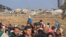 FILE —Palestinians fleeing the fighting in war-torn Gaza walk on a road while monitored by Isaeli soldiers (background) guarding Palestinian detainees in a military truck, in the Zeitoun district of the southern part of the Gaza Strip on November 19, 2023.