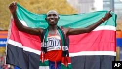 Geoffrey Mutai of Kenya holds the Kenyan flag after winning the men's division of the New York City Marathon, Nov. 3, 2013. 