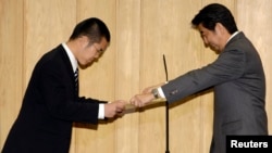 Shanghai-born Yan Jun, receives a certificate of appreciation from Japan's Prime Minister Shinzo Abe for saving a nine-year-old boy from a typhoon-swollen river in Osaka on Sept. 16.
