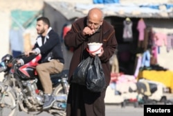 FILE - A man eats food that was distributed as aid in a rebel-held besieged area in Aleppo, Syria, Nov. 6, 2016.