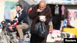 Homme ayant reçu une ration de nourriture distribuée dans une zone assiégée par les rebelles à Alep, en Syrie, le 6 novembre 2016.