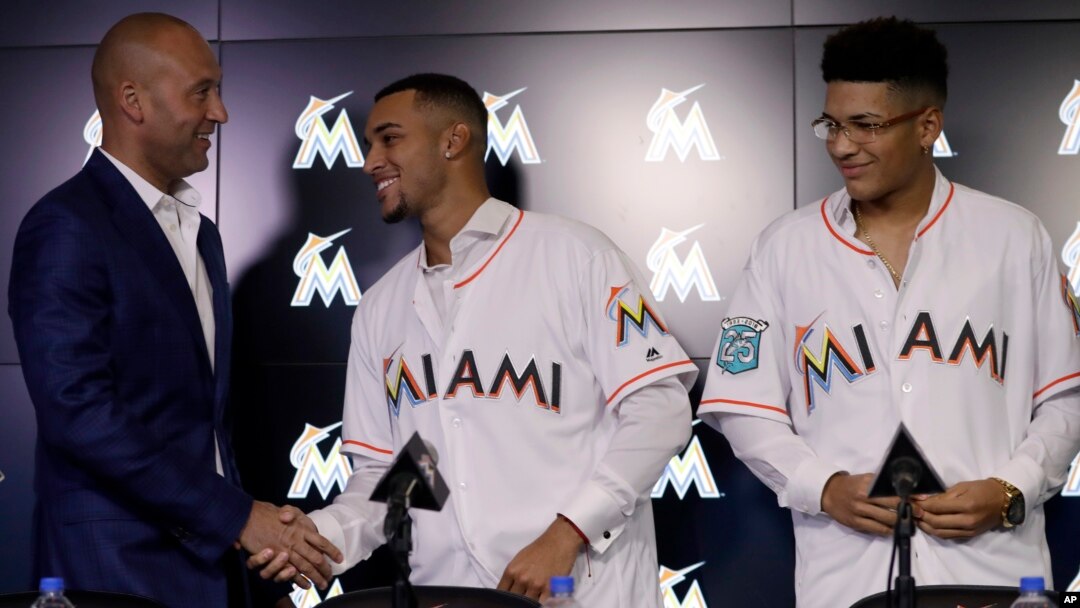 CEO Miami Marlins, Derek Jeter, kiri, berjabat tangan, berjabat tangan dengan Victor Victor Mesa, tengah, sementara saudara lelakinya Victor Mesa, Jr. mengamati dalam sebuah konferensi pers, Senin, 22 Oktober 2018 di Miami, Florida, AS (foto: AP Photo/Lynne Sladky)