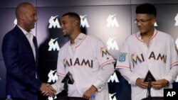 CEO Miami Marlins, Derek Jeter, kiri, berjabat tangan, berjabat tangan dengan Victor Victor Mesa, tengah, sementara saudara lelakinya Victor Mesa, Jr. mengamati dalam sebuah konferensi pers, Senin, 22 Oktober 2018 di Miami, Florida, AS (foto: AP Photo/Lynne Sladky)