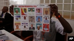 FILE - An election official shows a placard with different candidates during elections in Niamey, Niger, Feb 21, 2016.