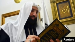 Islamist preacher Omar Bakri takes a look at a religious book during an interview with Reuters at his home in Tripoli, northern Lebanon, May 24, 2013.