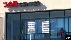 FILE - A man walks past the signs of an employment agency, March 2, 2021, in Manchester, N.H. 