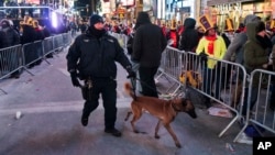 A New York City canine police officer walks past revelers gathered on Times Square in New York, Dec. 31, 2017.