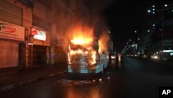 FILE - A bus stands in flames after it was set afire by opposition supporters trying to defy a ban on protests, in Dhaka, Bangladesh, Oct. 25, 2013.