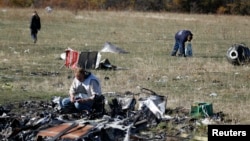 FILE - Members of a recovery team work at the site where downed Malaysia Airlines flight MH17 crashed, near the village of Hrabove, Donetsk region, eastern Ukraine, Oct. 13, 2014.